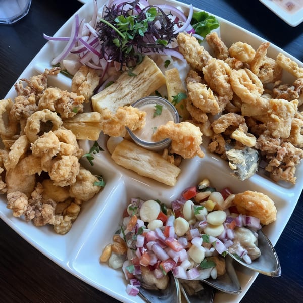 A white platter of Chios Peruvian Grill's fried seafood, yucca, and ceviche with red onions and corn.