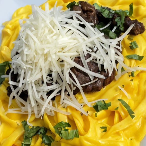 Peruvian pasta with yellow huancaina sauce, beef, shredded cheese, and green herbs.