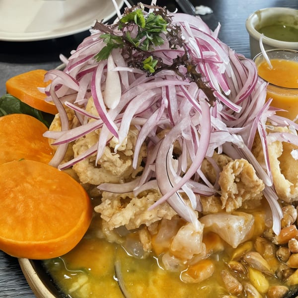 Peruvian ceviche with red onions, fried seafood, sweet potato, and corn in a yellow sauce.