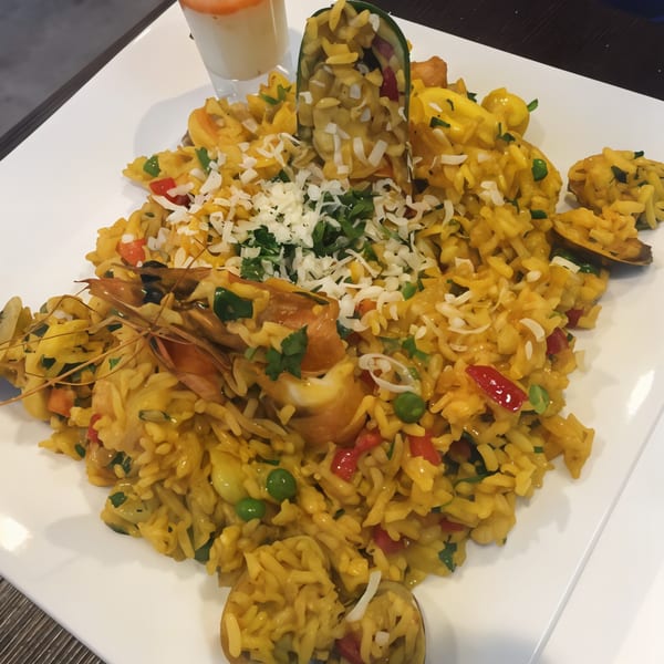 Peruvian arroz con mariscos, a yellow rice dish with shrimp, mussels, peas, and red peppers.