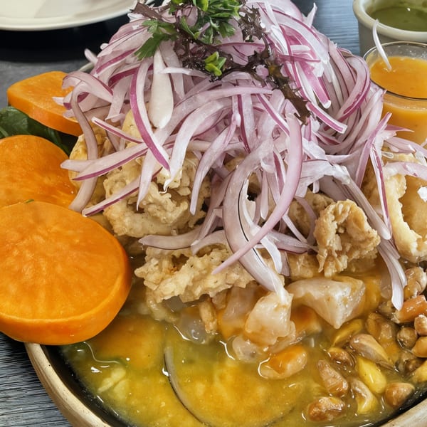 Peruvian ceviche with fried calamari, red onions, sweet potato, and corn in a yellow sauce.