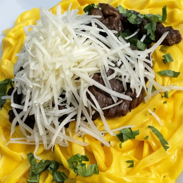 Peruvian pasta with yellow huancaina sauce, beef, shredded white cheese, and green herbs.