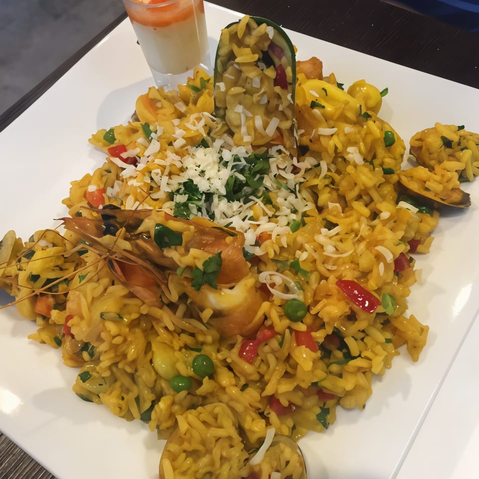 Peruvian seafood paella with shrimp, mussels, peas, and red peppers, topped with cheese and parsley.