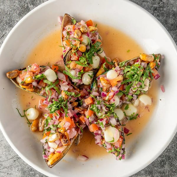 Peruvian ceviche with mussels, red onions, corn, and cilantro in a star-shaped arrangement.